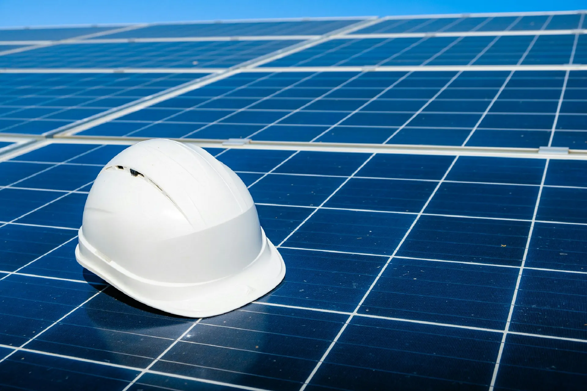 White safety hard hat resting on a blue solar panel