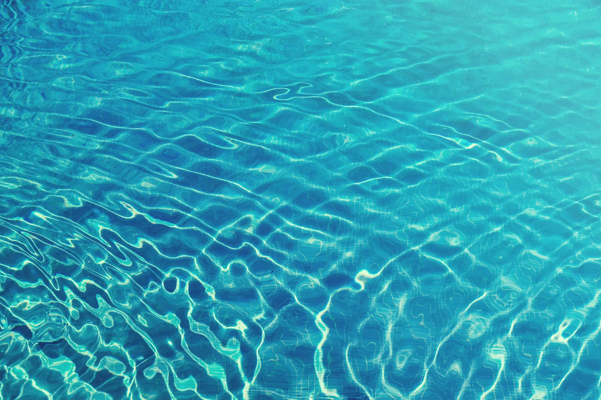 Sunlight rippling across clear turquoise pool water