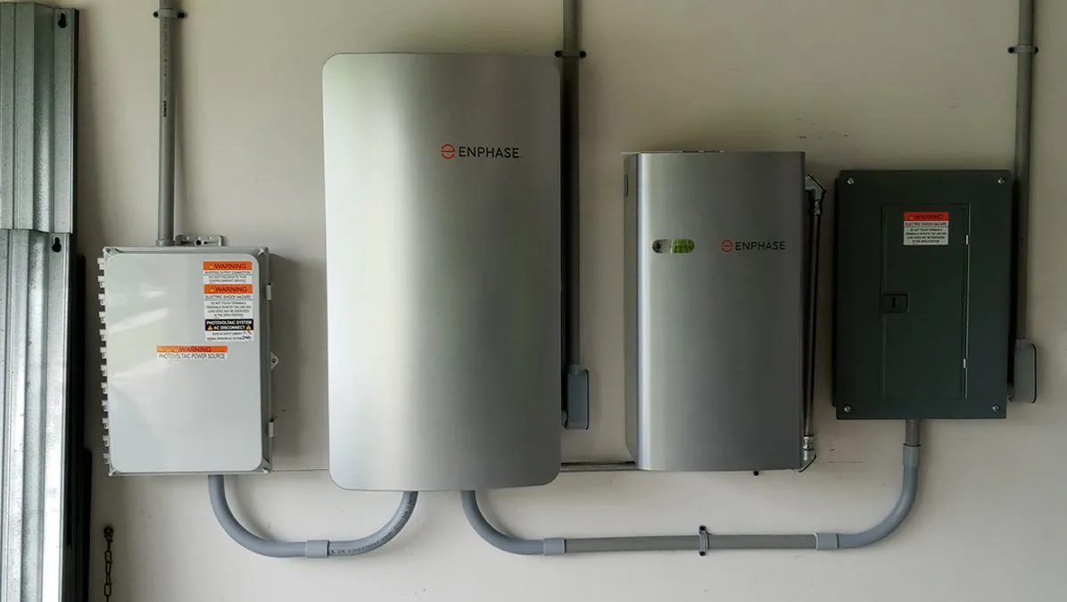 Home battery cabinets and an inverter mounted on a garage wall with tidy conduit runs