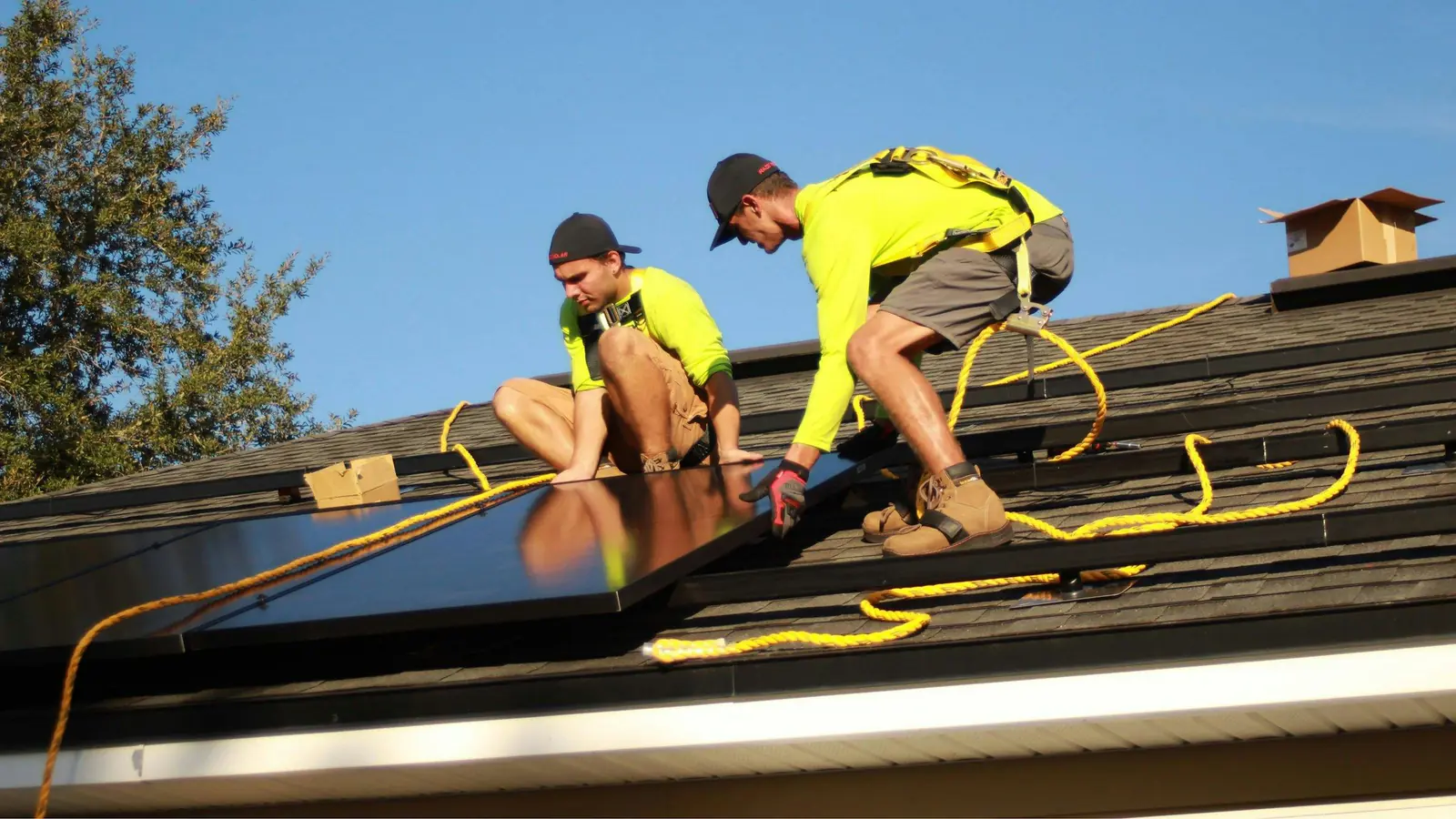 Solar technicians working together to fit panels on a sunny residential roof