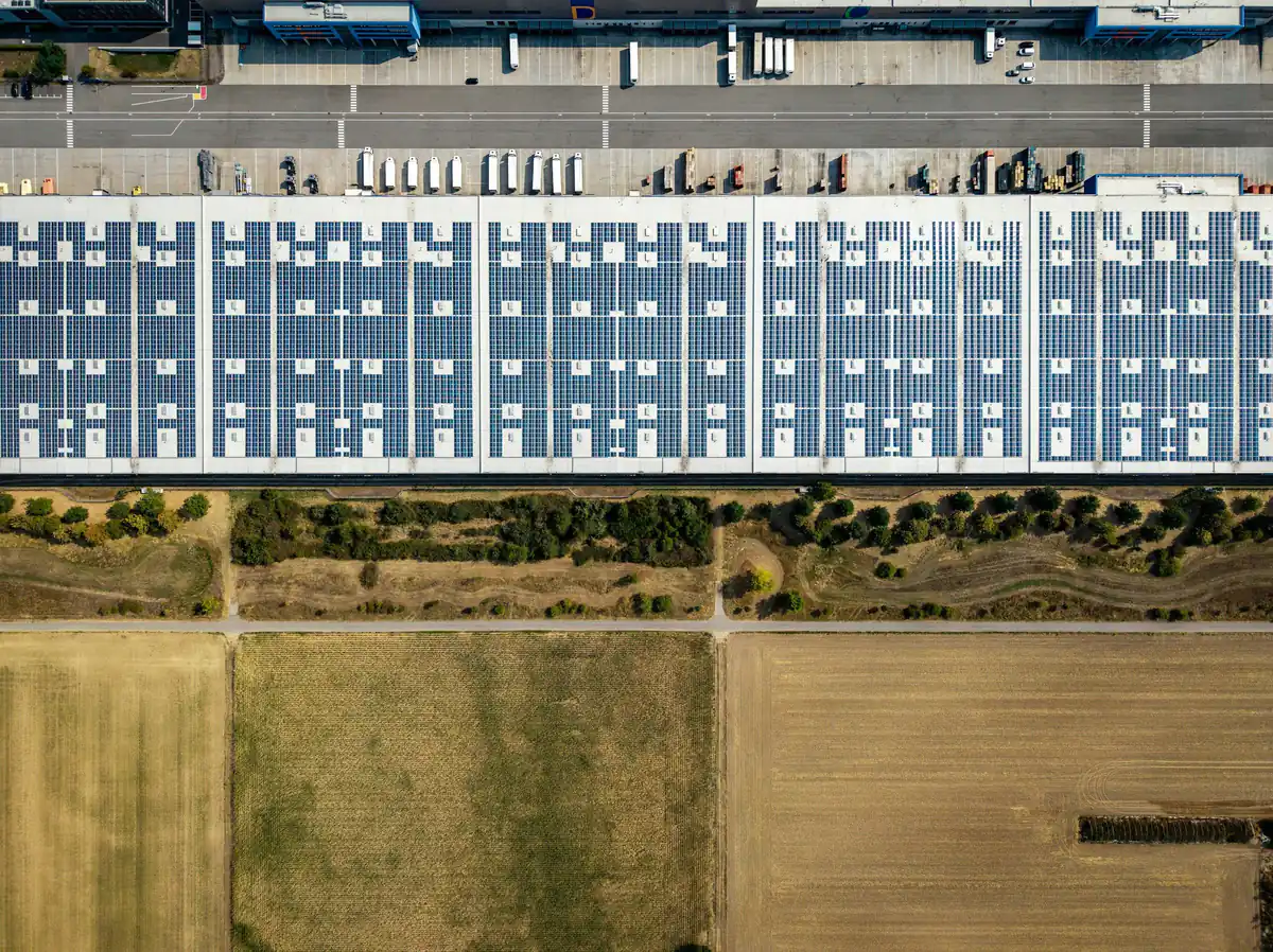 Aerial view of a large warehouse roof covered in rows of solar panels