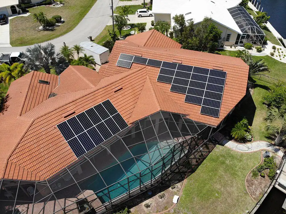 Aerial view of solar panels on a terracotta tile roof above a screened pool