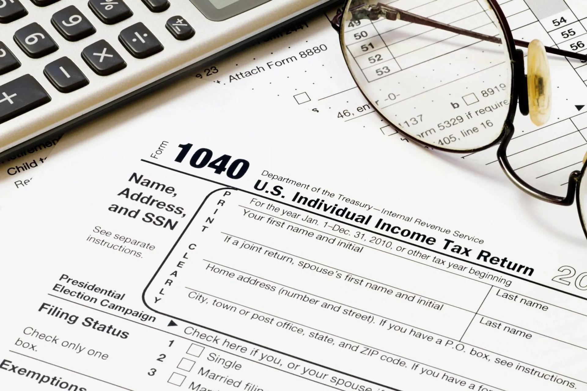 Calculator, reading glasses and a printed income tax form on a desk